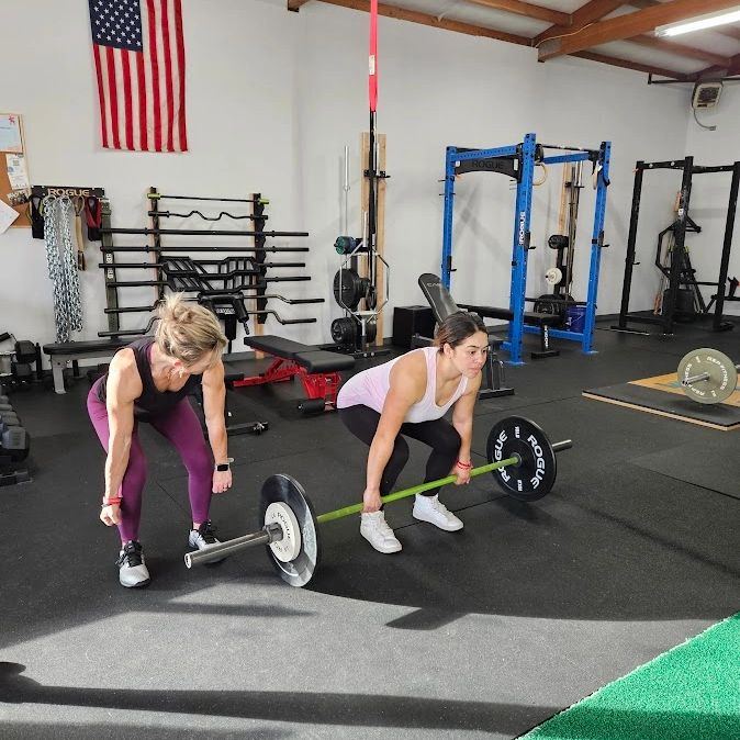 Two women lifting weights in a gym.