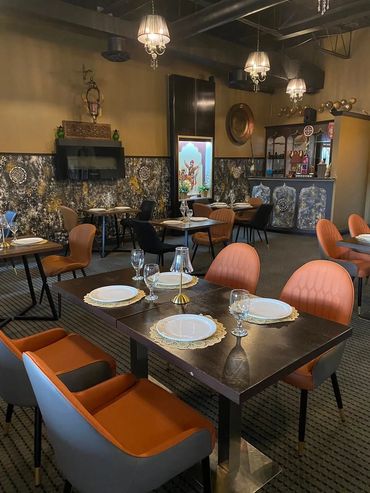 Elegant dining area with modern orange and black chairs and decorative lighting.