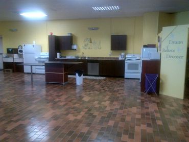Spacious kitchen with brown tiled floor and yellow walls.