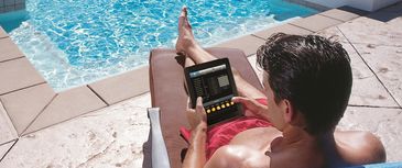 Man by a pool using an iPad to access his home audio system
