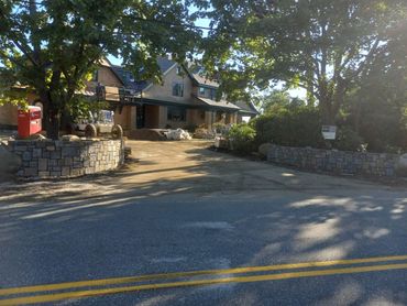 Stone walls and a house under construction with construction equipment and trees.
