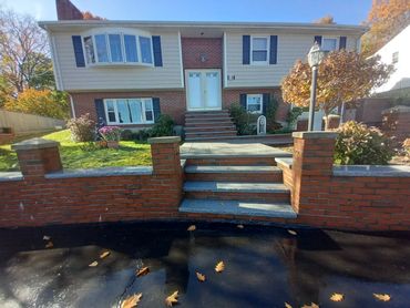 Front of a brick house with steps and a garden in autumn.