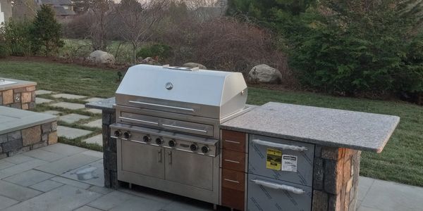 Modern outdoor kitchen with stainless steel grill and stone countertop.