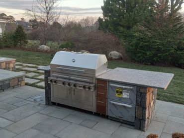 Modern outdoor kitchen with stainless steel grill and stone countertop.