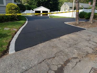 Newly paved driveway with caution tape blocking access.