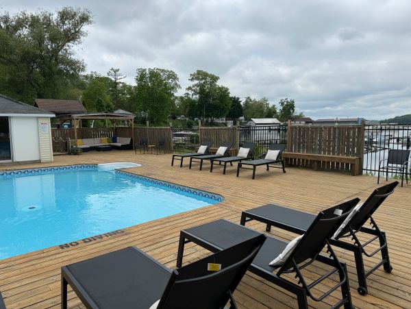Empty poolside deck with lounge chairs on a cloudy day.