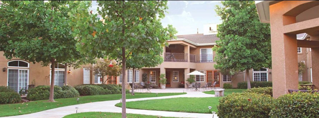 Peaceful courtyard with trees and seating areas in an apartment complex.