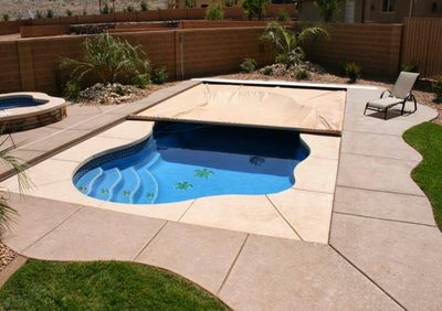 A small backyard pool with a partially covered safety cover and a single lounge chair.