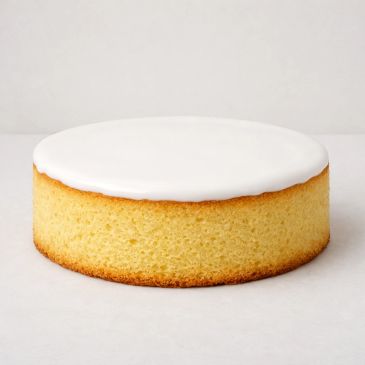 A round sponge cake with white icing on top.
