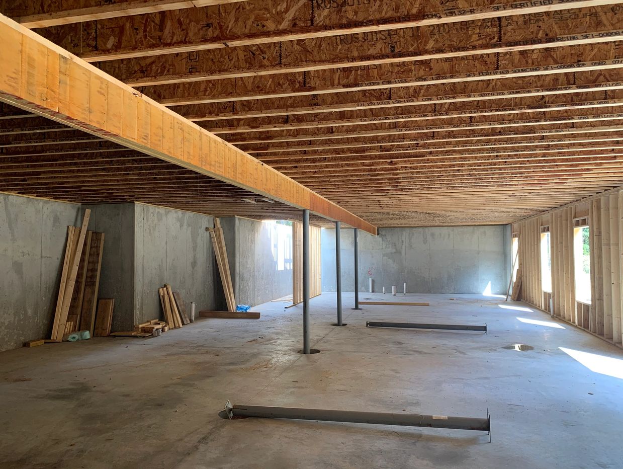 Unfinished basement with exposed ceiling beams and concrete walls.