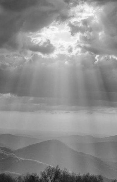 Sun rays breaking through clouds over mountains.