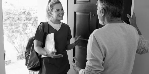 Friendly Home Health Care worker greeted by a home health services patient in their doorway