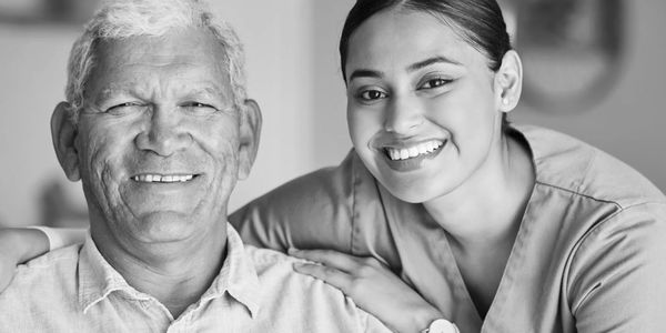 Home Health Care Nurse smiling at the camera  with her patient looking healthy and happy at home