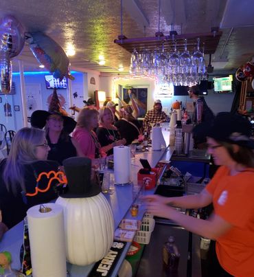 People enjoying a festive Halloween-themed night at a bar.