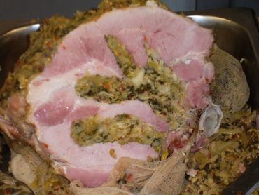 Close-up of a stuffed ham roll sliced to reveal a vegetable filling.