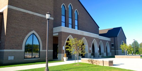 Modern brick building with gothic-style arched windows and bright blue sky.