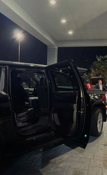 Black SUV with open rear door under bright lights at night.