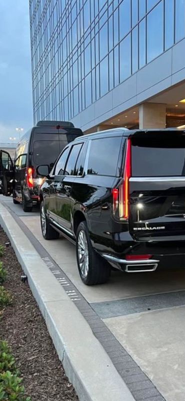 Two black vehicles parked outside a modern glass building.
