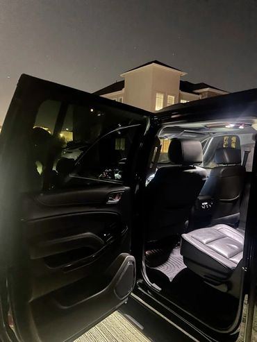 Open car door showing illuminated, clean interior at night.