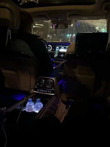 Luxurious car interior with ambient blue lighting and driver at night.