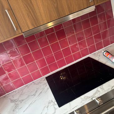 Modern kitchen backsplash with red tiles and marble countertop.