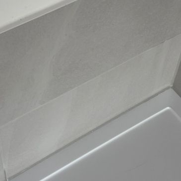 Close-up of a bathroom wall and bathtub corner with clean tiles.