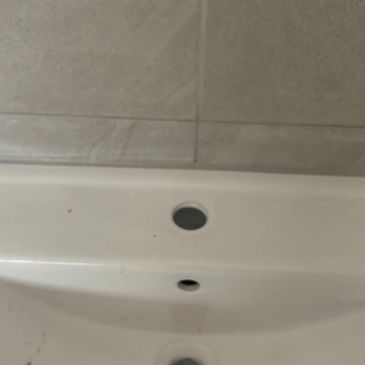 Close-up of a white bathroom sink with two empty faucet holes.