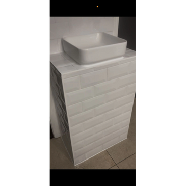 White rectangular sink on a tiled pedestal in a bathroom.
