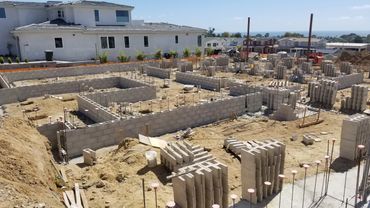Construction site with concrete block foundation walls under clear sky.