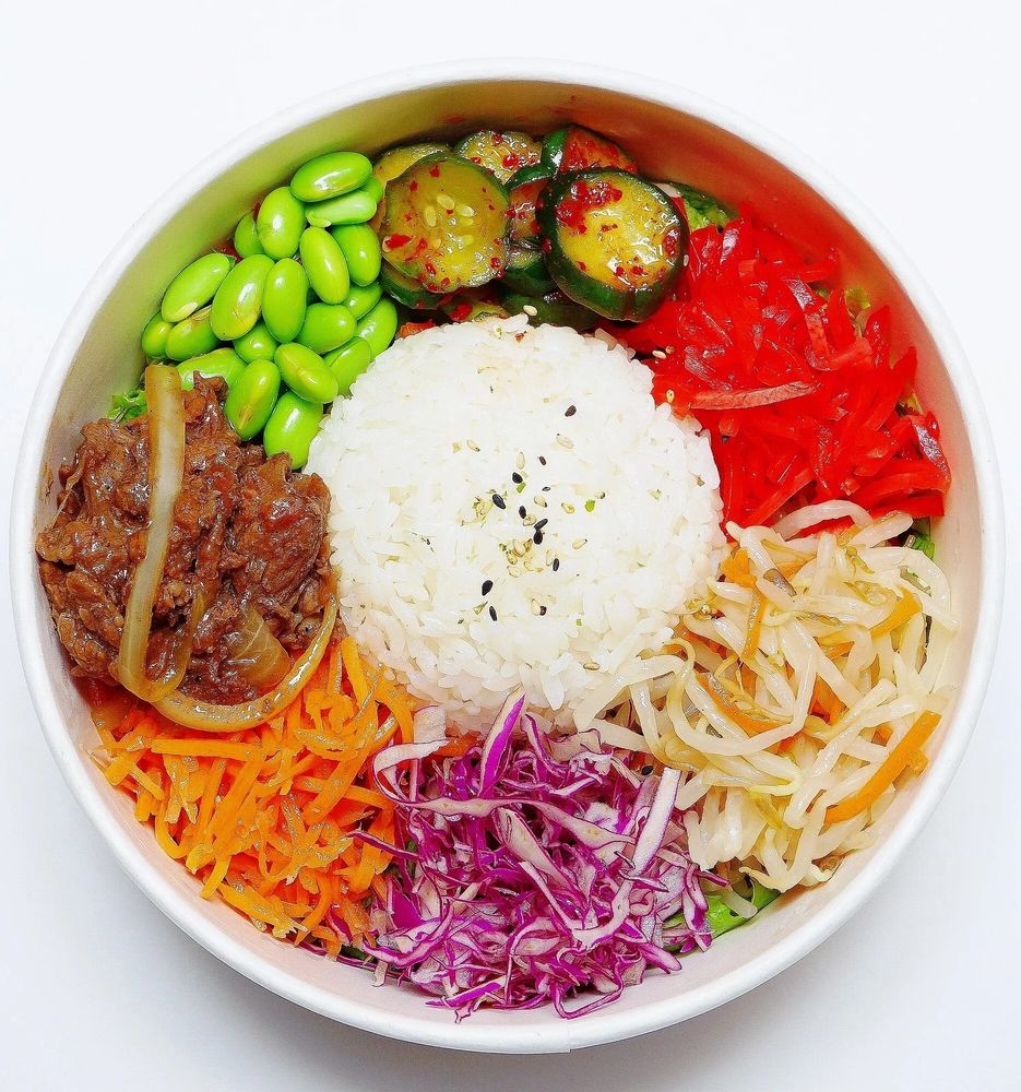 A colorful rice bowl with beef, vegetables, and edamame.