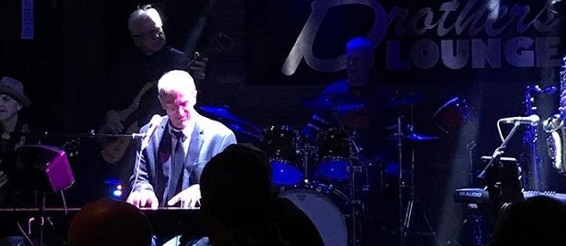 Mike Petrone in concert at Brothers Lounge bathed in blue light.