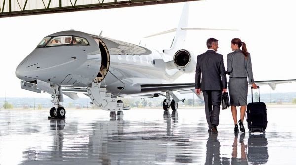 A business couple walking to a private jet in a hangar.