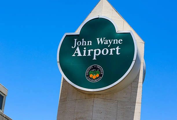 John Wayne Airport sign against a clear blue sky.
