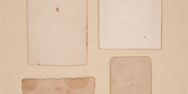 Four old blank paper pieces arranged on a beige surface.