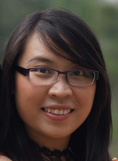 Smiling woman with glasses and long dark hair.