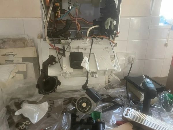 Boiler repair in progress with internal components exposed and tools on surrounding worktop