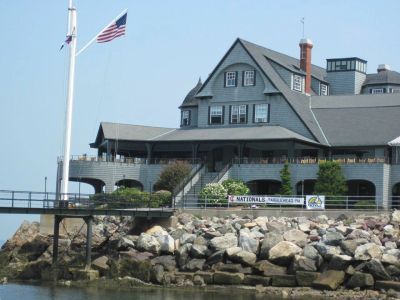 Large gray building by rocky shoreline with American flag.