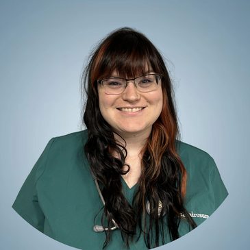Smiling female healthcare professional in green scrubs and glasses.