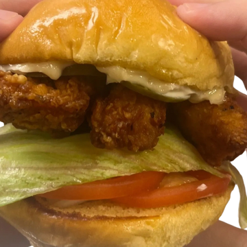 Close-up of a fried chicken sandwich with lettuce and tomato.