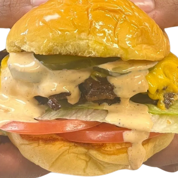 Juicy cheeseburger with creamy sauce dripping down.