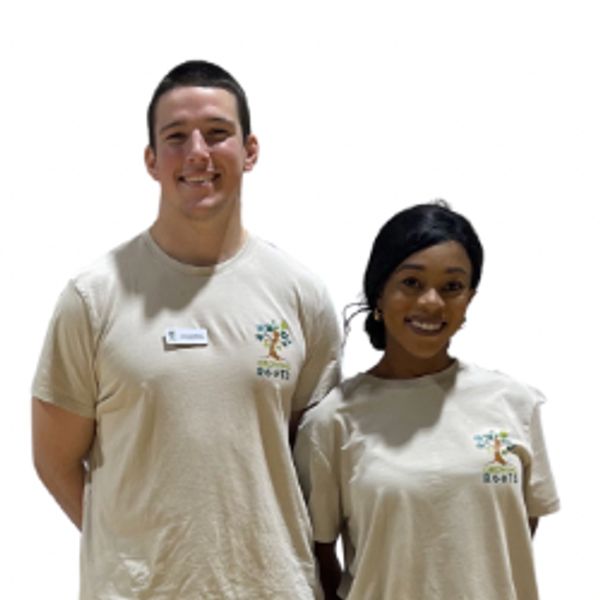 Two smiling volunteers wearing matching beige shirts with a colorful logo.