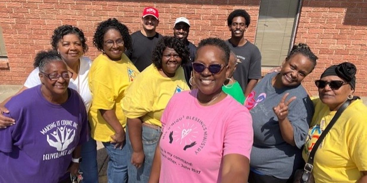 Group of smiling people posing outdoors, enjoying sunny day.