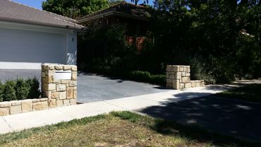 Stone pillars flank a driveway entrance with a mailbox on the left.