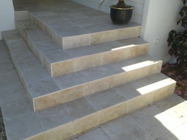 Stone tiled steps leading to a porch with a potted plant.