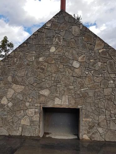 Stone structure with a triangular shape and an empty rectangular opening at the base.