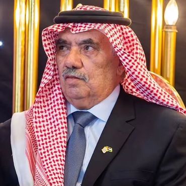 Elderly man in traditional Middle Eastern attire with a suit and tie.