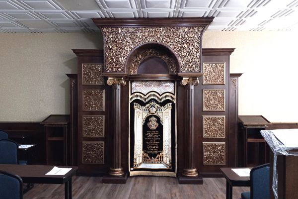 Ornate wooden ark with decorative details and a Torah curtain.