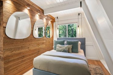Cozy modern bedroom with wooden accent wall and asymmetrical mirrors.