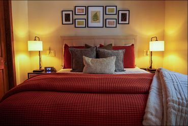 Cozy bedroom with warm lighting and red bedding.