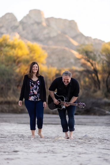 Male and female members of an acoustic cover band laughing together in a wash near Tucson, AZ